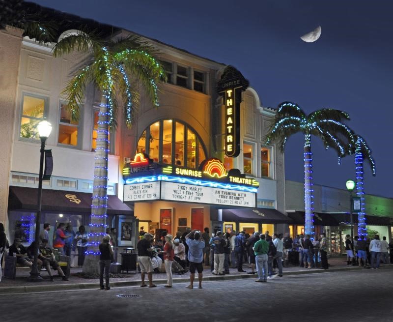 Outside of the Sunrise Theatre in downtown Fort Pierce at night with a crowd of people waiting to get inside.